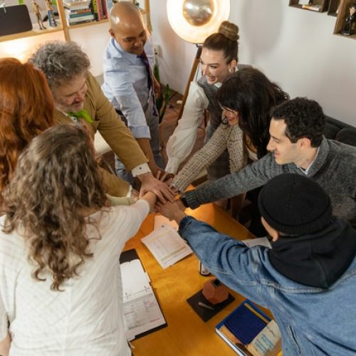 People in a meeting doing a "hands in" type huddle