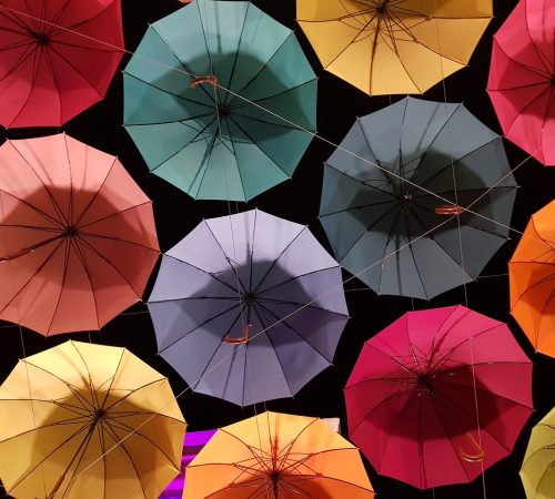 A bunch of umbrellas, with different colours, arranged in a zig-zag pattern